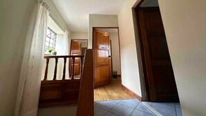 Un pasillo con escaleras de madera, una puerta grande de madera y un candelabro colgante.