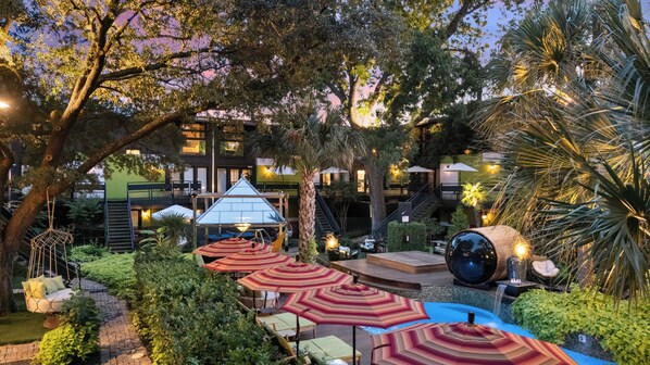 An outdoor patio area with seating, umbrellas, and a pool.