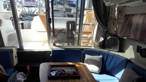 A cozy cabin interior with a wooden table, blue cushioned seating, and a view of boats and a bridge outside. - Yacht rental Downtown Providence (Providence)