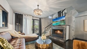 Un salon moderne doté d’une cheminée, d’un grand téléviseur et d’un espace salon confortable.