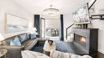 A modern living room with a fireplace, leather sofa, and a chandelier.