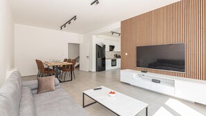 Ett modernt vardagsrum med en grå soffa, ett soffbord och en tv som är monterad på en vägg av trä.