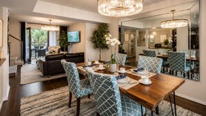 A dining area with a wooden table, blue patterned chairs, and a chandelier. - 2-story loft oasis on the second floor, featuring a pool, lush courtyard views, and a prime Lower Greenville location. (Dallas)