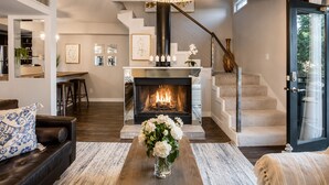 A modern living room with a fireplace, a staircase, and a dining area. - 2-story loft oasis on the second floor, featuring a pool, lush courtyard views, and a prime Lower Greenville location. (Dallas)