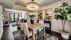 A dining area with a wooden table, chairs, a chandelier, and a large mirror on the wall. - Spacious 2-story loft with king suite, fireplace, and resort-style amenities. (Dallas)