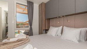 A hotel room with a bed, a view of the outside, and a balcony.