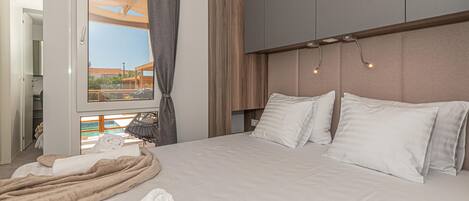 A hotel room with a bed, a view of the outside, and a balcony.