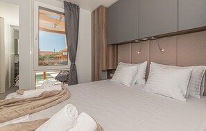 Relax in comfort with a large bed, wooden headboard, and balcony offering a view.