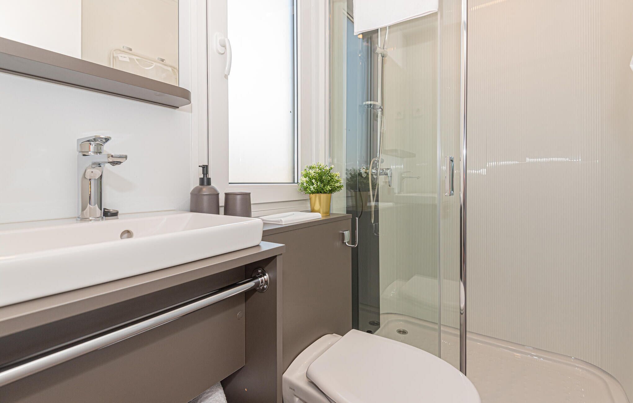 Une salle de bain moderne avec un lavabo blanc, une douche en verre et des toilettes.