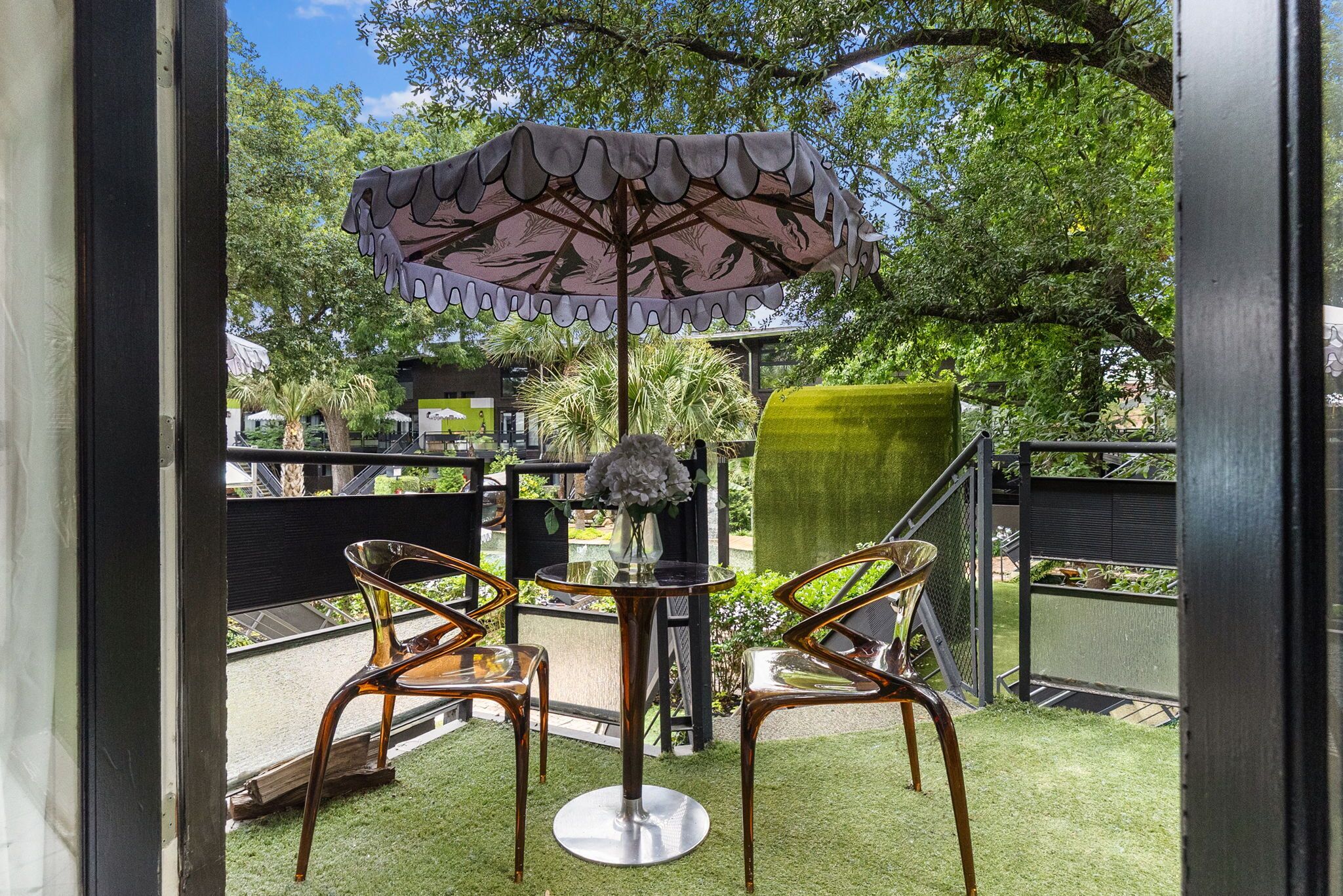 A patio with two chairs, a table, and a decorative umbrella.