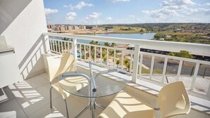 A balcony with a glass table and chairs, overlooking a body of water and a distant landscape. - Resort do Lago - dinamicaTur (Caldas Novas)