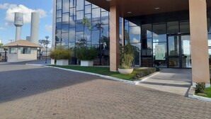 A modern building with a glass facade, a paved entrance area, and a small garden with potted plants. - Resort do Lago - dinamicaTur (Caldas Novas)