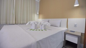A hotel room with a large bed, a nightstand, a lamp, and a window with curtains. - Resort do Lago - dinamicaTur (Caldas Novas)