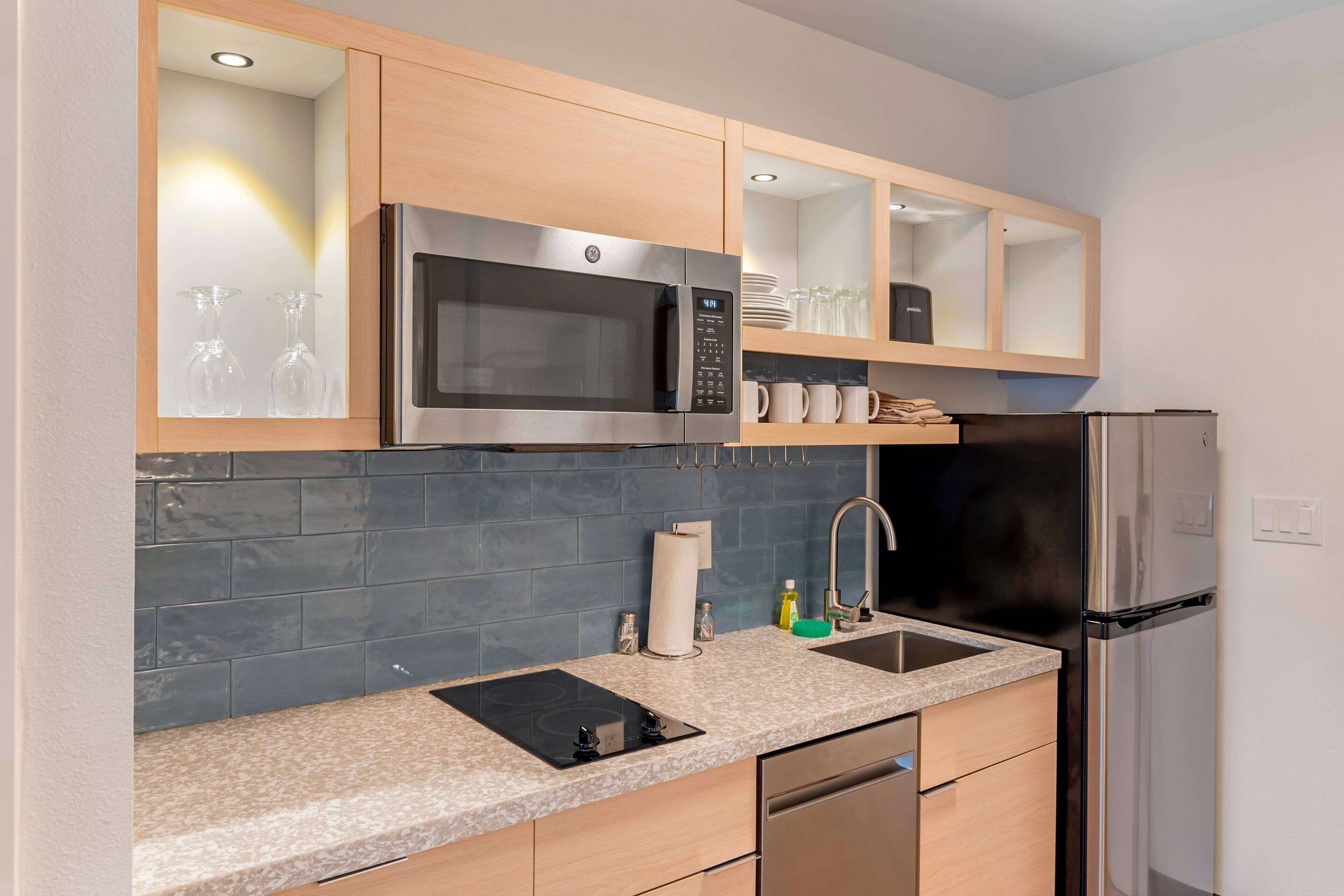 A modern kitchen with a stainless steel microwave, a built-in oven, a sink, and a dishwasher.
