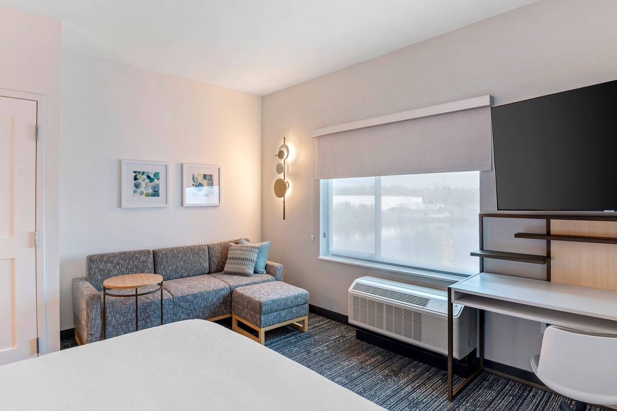 Une chambre d’hôtel moderne équipée d’un lit, d’un bureau, d’un canapé et d’une grande fenêtre.