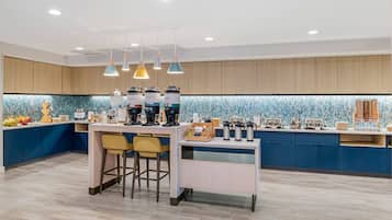 A modern kitchen with a central island, bar stools, and a coffee station.