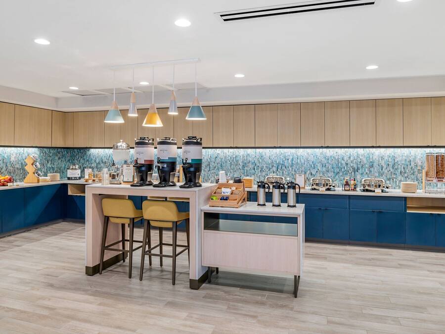 A modern kitchen with a central island, bar stools, and a coffee station.
