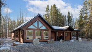 Une cabane dotée d’un toit à pignon, de grandes fenêtres et d’une allée gravillonnée.
