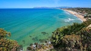 Une vue sur la côte, avec une eau turquoise cristalline, une plage de sable et une ville en arrière-plan.