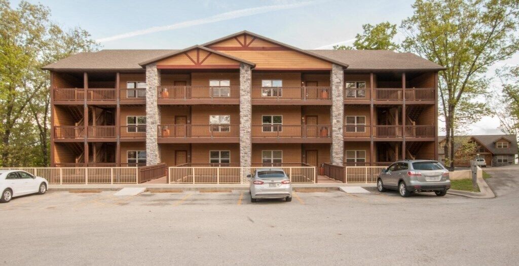A multi-story hotel with balconies, a parking lot, and a clear sky.
