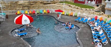 A swimming pool area with multiple lanes, lounge chairs, and umbrellas.