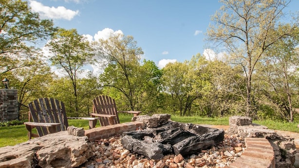 An outdoor seating area with a stone fire pit surrounded by Adirondack chairs.