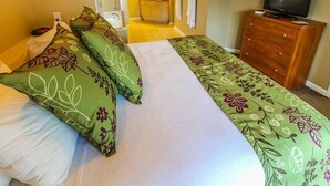 Una habitación de hotel con cama, televisión, cómoda de madera y baño a la vista.