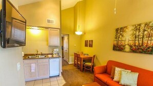 A compact living space with a kitchenette, a dining area, and a sofa. - Capital Vacations Carriage Place - 1 Bedroom (7-Night) (Branson)