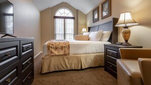 Une chambre à coucher avec un lit, un ventilateur de plafond, une fenêtre, une commode et une lampe.