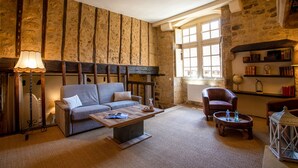 Een gezellige woonkamer met een stenen muur, een bank, een salontafel, een stoel en een boekenkast.