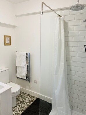 Kylpyhuone, jossa on suihku, wc ja pyyheteline.