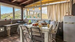 Cocina compacta con una mesa de comedor, sillas, refrigerador y una ventana con cortinas.