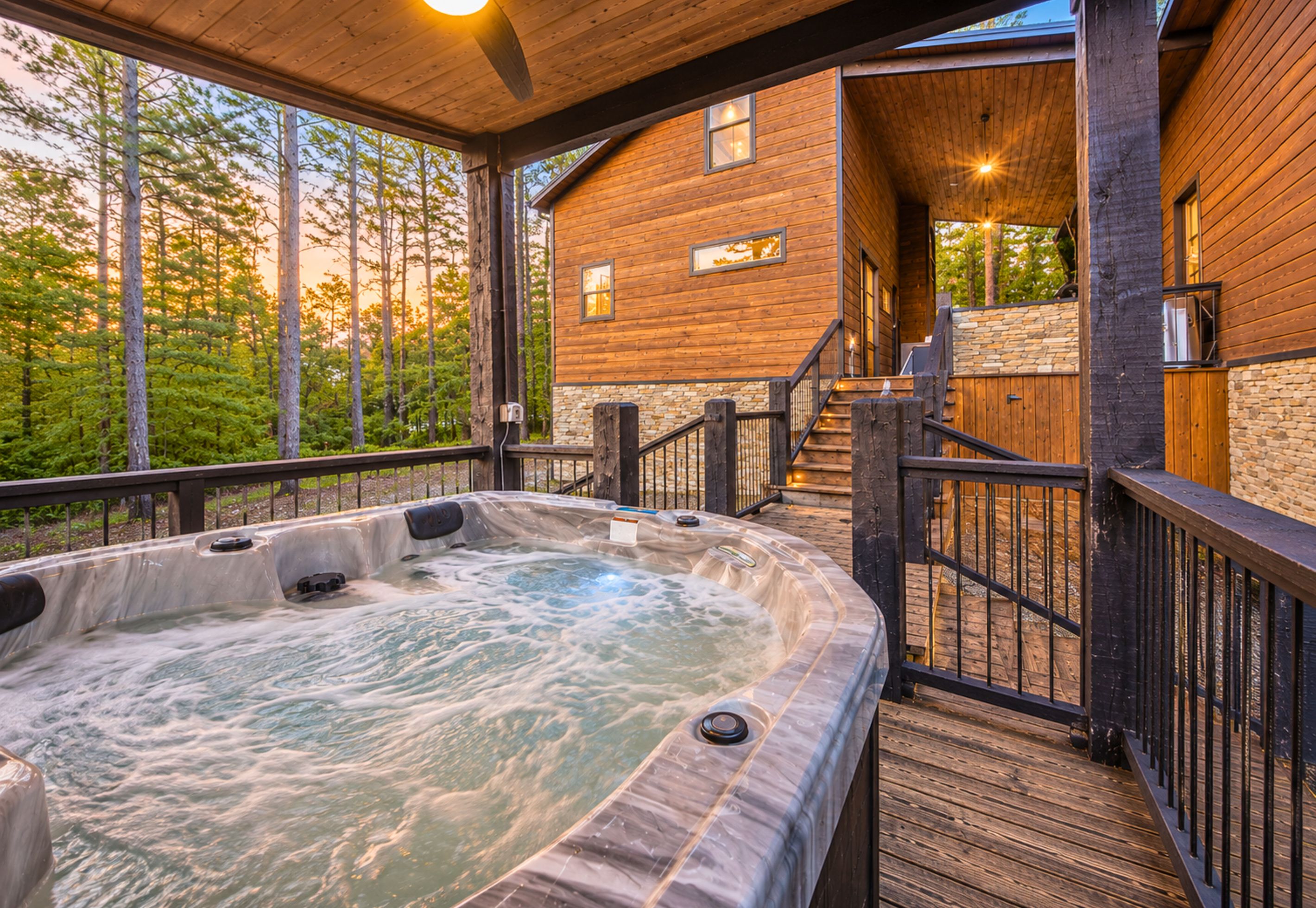 A hot tub on a wooden deck with a view of a cabin.