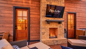 Una zona de estar exterior acogedora con mobiliario de mimbre y una chimenea de piedra.
