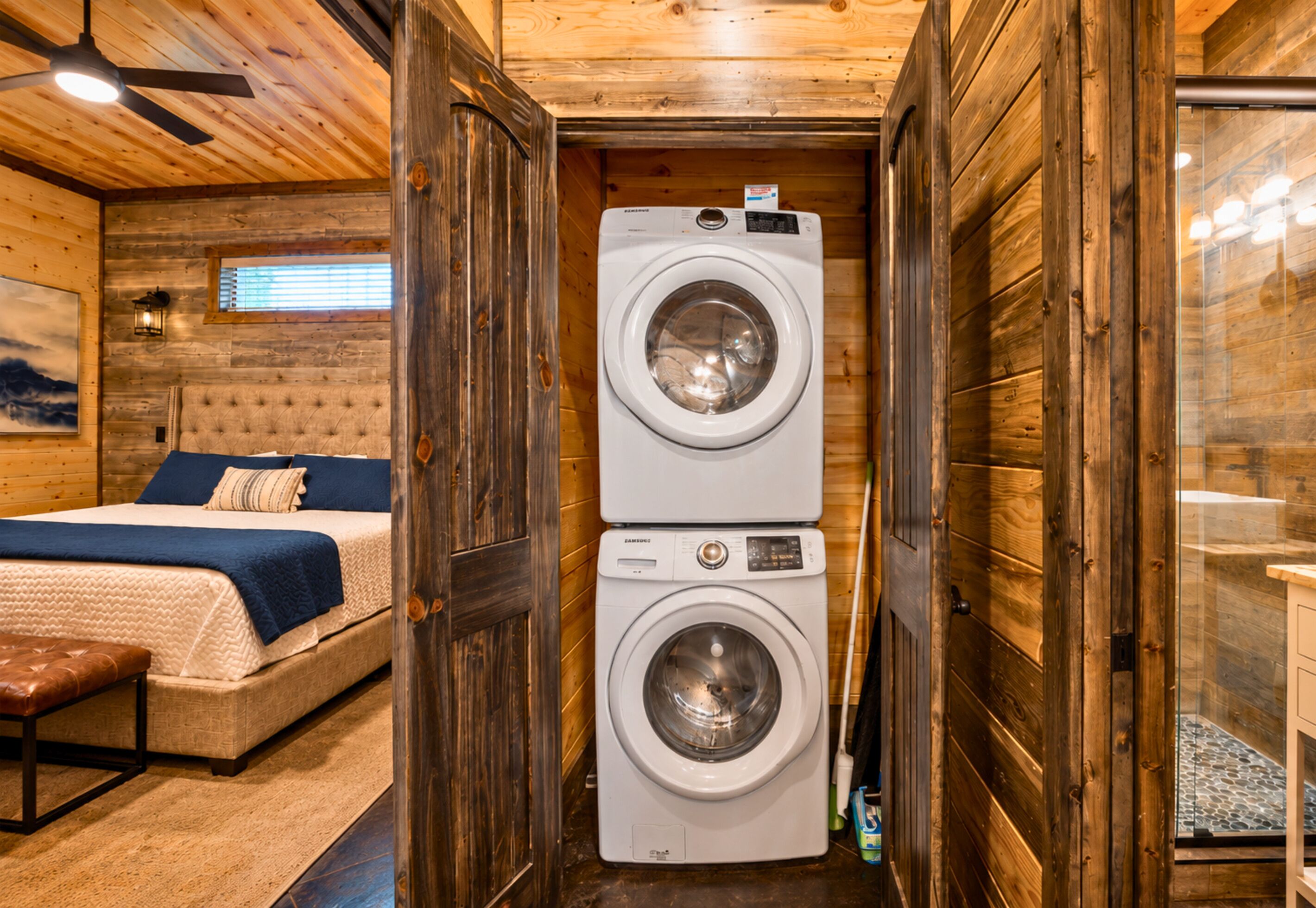 A compact room with a bed, a washing machine, and a bench.