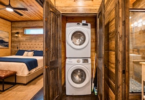 A compact room with a bed, a washing machine, and a bench.