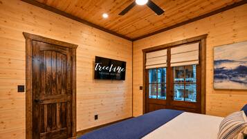 A wooden interior with a bed, a door, and a sign for TreeLine Vacation Rentals.