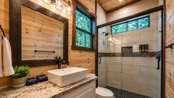 A modern bathroom with a large mirror, a sink, and a shower area.