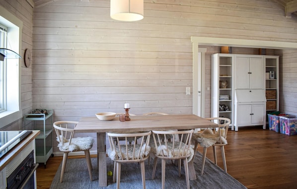 A dining area with a wooden table and chairs, a rug, and a kitchen area with cabinets and a refrigerator. - Beautiful home in Aremark with kitchen (Aremark)