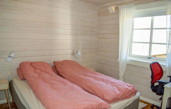A single bed with pink bedding in a room with wooden walls and a window. - Beautiful home in Aremark with kitchen (Aremark)