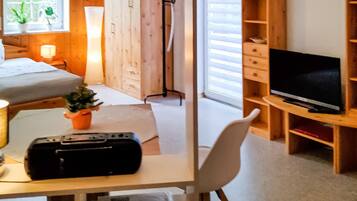 Ein Schlafzimmer mit einem Bett, einem Schreibtisch mit Computer, einem Fernseher und einem Bücherregal.