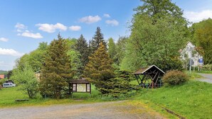 A rural road with a gravel path, a wooden shelter, and a signboard.