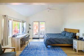 A bedroom with a bed, desk, chair, and a view through a door.