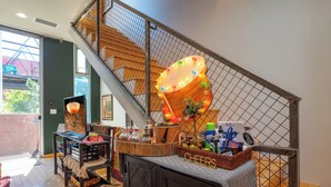 A staircase with a decorative light fixture, a basket with a 'CHEERS' sign, and a table with various items. - Industrial Luxury Updated condo, 5 mins to Railyard, 7 mins to Plaza (Santa Fe)