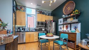 A modern kitchen with wooden cabinets, stainless steel appliances, and a round table with chairs. - Industrial Luxury Updated condo, 5 mins to Railyard, 7 mins to Plaza (Santa Fe)