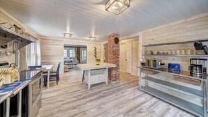 A modern kitchen with wooden flooring, a central island, and a brick accent wall. - Colton's Cabin (Hawley)