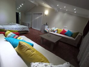 Una sala acogedora con un sofá, una mesa de centro y una cama con almohadones de colores.