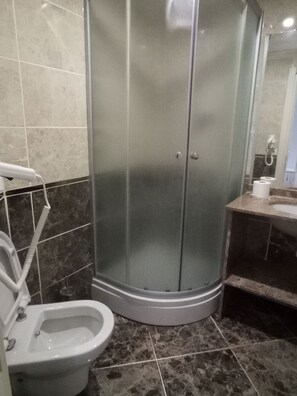 Un baño con ducha envuelta en vidrio, inodoro y lavamanos.