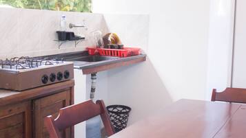 A kitchen with a gas stove, a sink, and a red basket on the countertop.