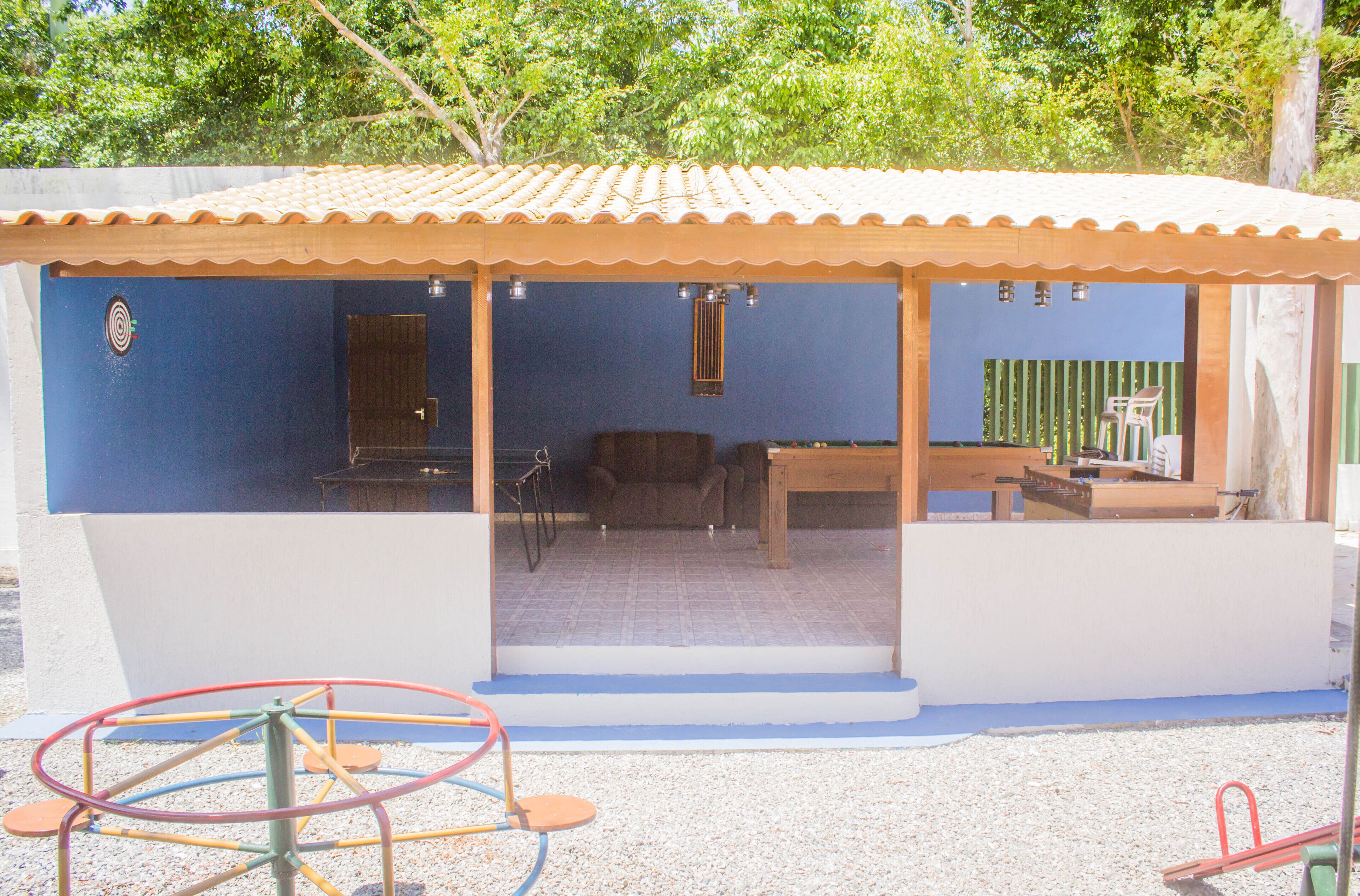 Uma área externa coberta com parede azul, uma mesa de madeira e uma cadeira.
